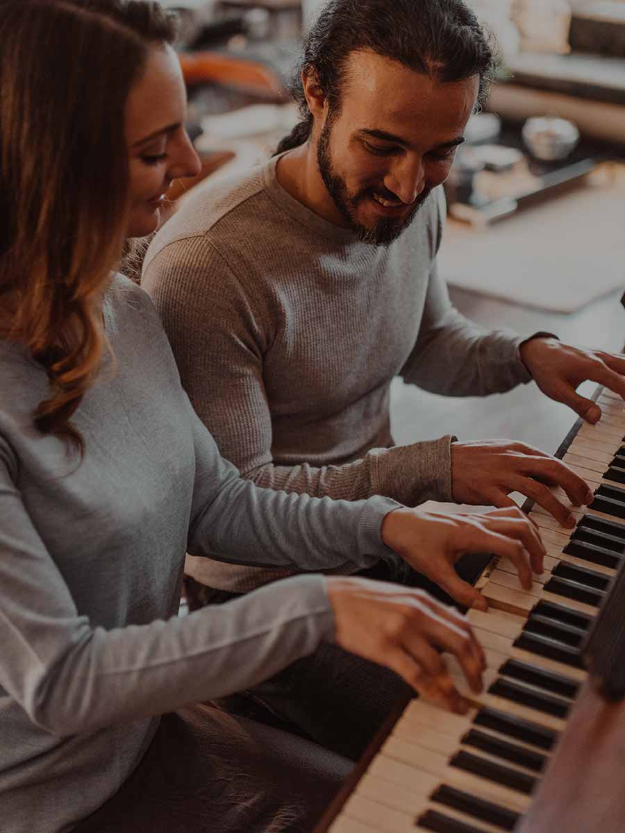 Couple learning to play the piano in a group format