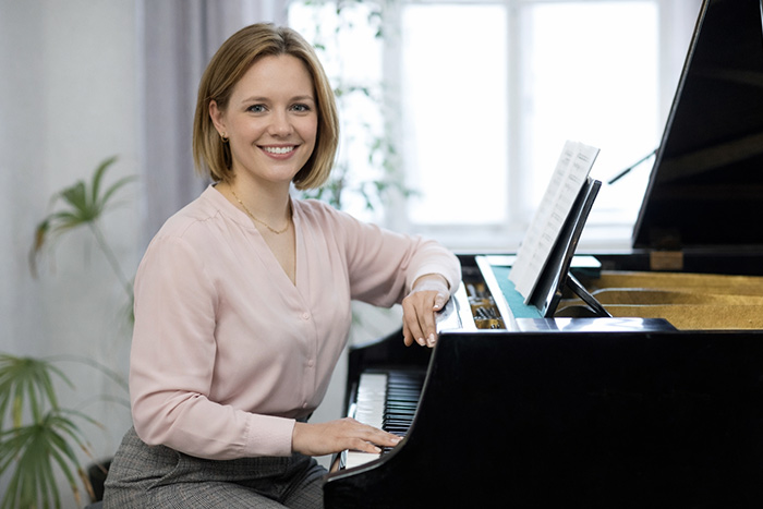 Lady pianist smiling and sitting on piano