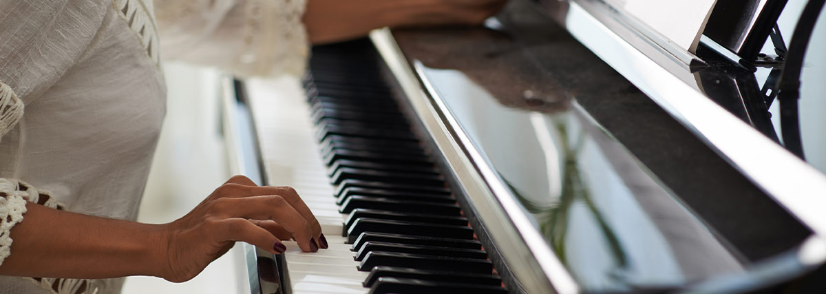 Pianist practising slowly at an upright piano while reviewing sheet music for improved technique