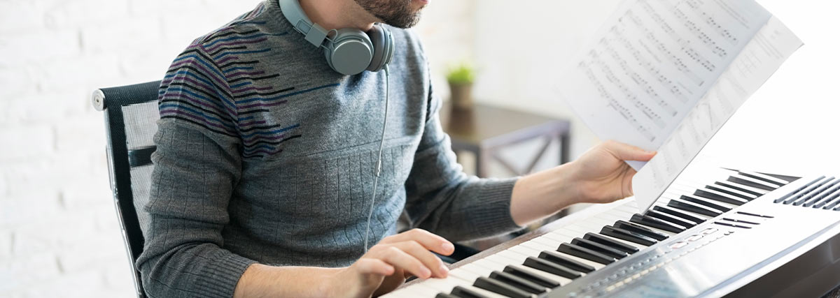 Piano student studying sheet music at a digital piano to practise challenging musical passages