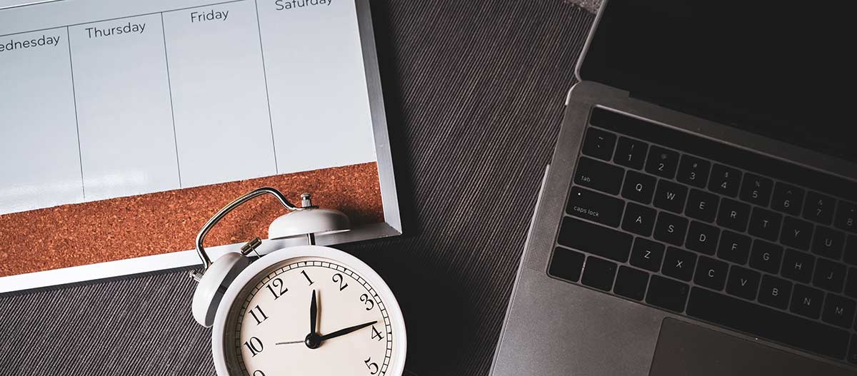 Laptop, clock and weekly planner representing music lessons for busy professionals