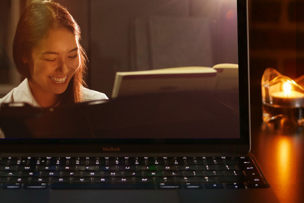 Woman smiling during an online piano lesson on her laptop