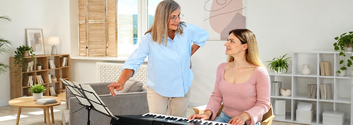 Adult piano teacher guiding a student during a lesson